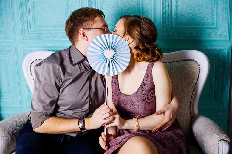 A Ukrainian girl kissing a man while covering with a fan.